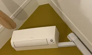 Een witte airco unit met een Daikin logo, netjes gemonteerd. De airco leidingen zijn weggewerkt in witte kokers, wat zorgt voor een strakke afwerking.