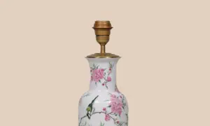Een lamp maken van vaas: een witte vaas met roze bloemen en een vogel, omgebouwd tot lamp met een gouden fitting.