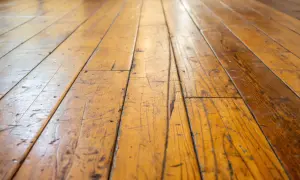 Gouden houten vloer met zichtbare krassen in gelakt hout, die verhalen vertellen van geleefde momenten.