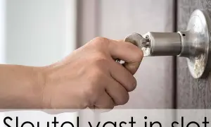 Hand probeert een sleutel in een deurklink te draaien, maar de sleutel zit vast in het slot en draait niet.