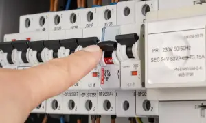 Vinger schakelt een zekering om, mogelijk om een kortsluiting op te sporen in de meterkast.