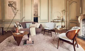Een elegante woonkamer waar klassiek en modern interieur combineren. Een paarse bank, witte fauteuils en houten accenten.