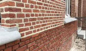 Gedetailleerd zicht op een nieuwe gevel plaatsen met rode bakstenen en wit voegwerk. De textuur van de stenen is duidelijk zichtbaar.