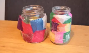 Twee glazen potjes, versierd met gekleurd papier en glitter, klaar voor kerst. Leuk om kerst potjes te maken!