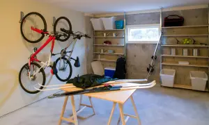 Een opgeruimde kelder met fietsen aan de muur, ski's op een tafel en opbergplanken vol spullen.