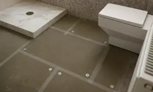 Badkamer in aanbouw, met een douchebak, toilet en voorbereiding voor plafond tegelen.