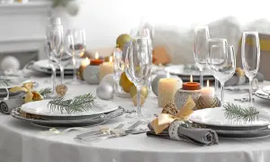 Een feestelijk gedekte tafel met glazen, kaarsen, kerstballen en dennentakjes. Klaar voor een gezellig diner!