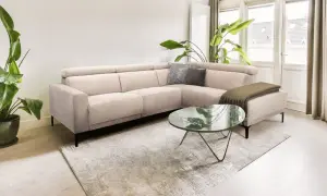 Licht beige hoekbank met kussens en plaid, een marmeren salontafel en grote planten creëren een rustig slow living interieur.