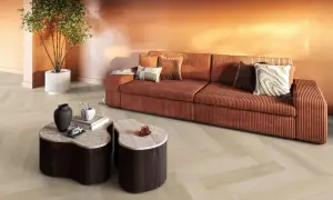 Een woonkamer met een oranje bank, marmeren tafels en een plant. De lichte evc vloer met visgraatmotief vormt een rustige basis.