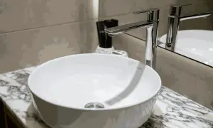 Moderne witte wasbak met een glanzende kraan. Er zijn lichte krassen in de wasbak te zien, die het dagelijks gebruik verraden.