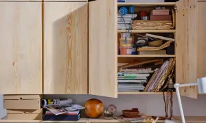 Een open houten kast met diverse spullen, waaronder stapels oud papier, tijdschriften en bakjes. Ideaal voor oud papier opbergen.