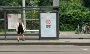 Een poster bij een bushalte met een symbool en de tekst "HIER HING FOSSIELE RECLAME". Dit is een oproep om geadresseerde reclame stopzetten.