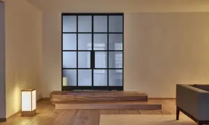 Een serene woonkamer met een glazen scheidingswand, houten elementen en een lamp, die de essentie van Japans minimalisme uitstraalt.