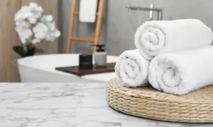 Frisse, witte handdoeken, net gewassen, liggen op een mandje in een luxe badkamer.