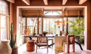 Warme, aardse tinten domineren deze eetkamer. De balken van het plafond zijn geschilderd in een lichte kleur, wat een mooi contrast vormt met de terracotta muren.