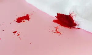 Bloedvlekken verwijderen? Oma weet raadt! Een witte doek absorbeert rode vlekken op roze ondergrond.