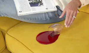 Een glas rode wijn is omgevallen op een gele bank. Hopelijk ruikt de bank straks weer lekker fris!