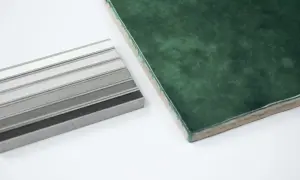 Een donkergroene tegel ligt naast een stapel grijze samples. Welke kleur voeg bij groene tegels?