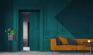 Een modern interieur waar groen en blauw combineren. Een okergele bank met donkerblauwe kussens staat voor een diepblauwe muur met sierlijke ornamenten.