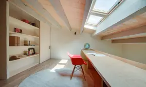Een opgeruimde zolder met een bureau, boekenkast en dakramen. Perfect voor een rustige werkplek.