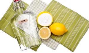Fles azijn, citroen en bakpoeder op groene theedoeken. Perfect voor het wassen van nieuwe handdoeken met azijn.