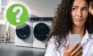 Vrouw met telefoon kijkt gefrustreerd naar wasmachine. Is er te weinig was in wasmachine?