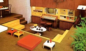 Een retro woonkamer met een **zitkuil jaren 70**, oranje en gele meubels, een orgel en een tv.