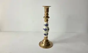 Een gouden kandelaar met een wit porseleinen deel, versierd met blauwe bloemen. Dit is wat vintage is: een stukje geschiedenis dat warmte en sfeer brengt.