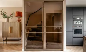 Moderne glazen schuifdeuren geven trapgat inspiratie. Een marmeren trap met donkere treden en een houten vloer.