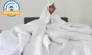 Vrolijke persoon verstopt zich in een berg wit dekbed. Het is een uitdaging om dit dekbed op te ruimen!