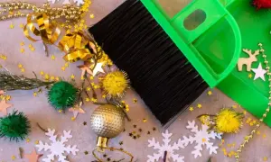 Een groene bezem en stoffer maken de kerstspullen op, met glitters, kerstballen en sneeuwvlokken verspreid.