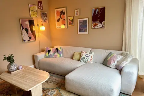 Een gezellige woonkamer met een lichte hoekbank, een salontafel en een inspirerende gallery wall maken.