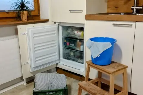 Vriezer niet goed dicht gedaan, met een blauwe emmer en doek klaar voor de ontdooiing.