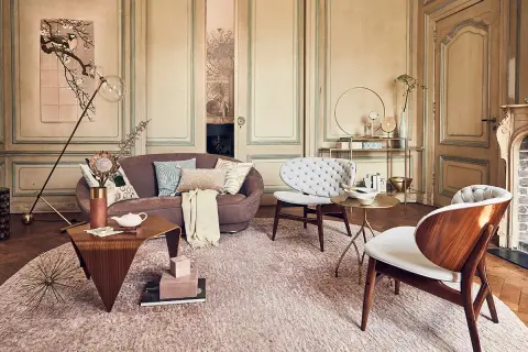 Een elegante woonkamer waar klassiek en modern interieur combineren. Een paarse bank, witte fauteuils en houten accenten.
