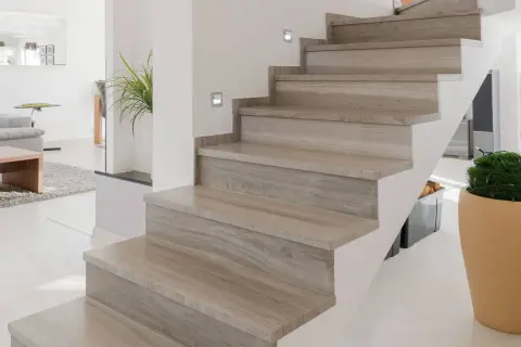 Moderne trap met houten look bekleding, perfect voor trap bekleden ideeen. Sfeervolle verlichting en planten maken het geheel af.