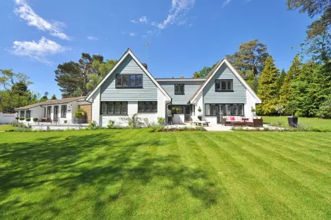 Een ruime woning met een aangebouwde garage, omringd door een perfect gemaaid gazon en bomen. Dit is een voorbeeld van wat een kangoeroewoning kan zijn: een woning met een apart woongedeelte.