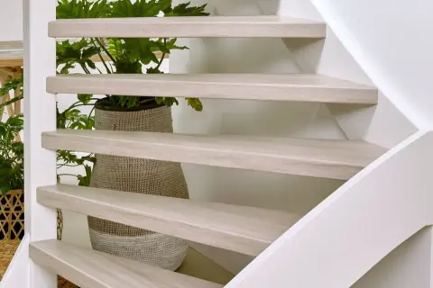 Lichte houten traptreden met planten erachter. Inspiratie voor open trap opknappen ideeën.