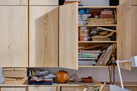 Een open houten kast met diverse spullen, waaronder stapels oud papier, tijdschriften en bakjes. Ideaal voor oud papier opbergen.
