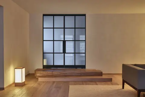 Een serene woonkamer met een glazen scheidingswand, houten elementen en een lamp, die de essentie van Japans minimalisme uitstraalt.