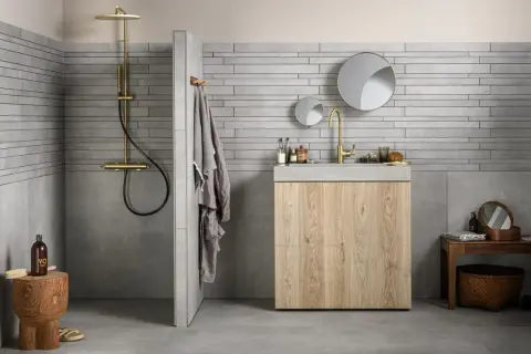 Grijze badkamer met houten meubel. Welke kleur handdoeken passen hierbij? Een grijze handdoek hangt aan de muur.