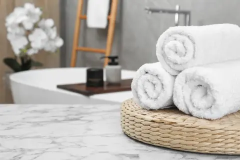 Frisse, witte handdoeken, net gewassen, liggen op een mandje in een luxe badkamer.