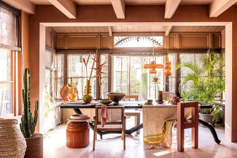 Warme, aardse tinten domineren deze eetkamer. De balken van het plafond zijn geschilderd in een lichte kleur, wat een mooi contrast vormt met de terracotta muren.