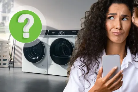 Vrouw met telefoon kijkt gefrustreerd naar wasmachine. Is er te weinig was in wasmachine?