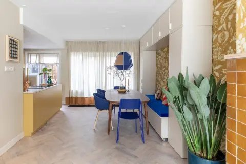 Een moderne eetkamer met een gele keuken en blauwe stoelen. De RAL 7006 combineren met de blauwe en gele accenten zorgt voor een levendige sfeer.