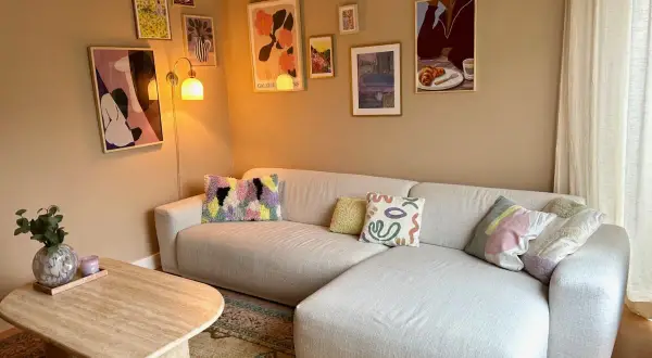 Een gezellige woonkamer met een lichte hoekbank, een salontafel en een inspirerende gallery wall maken.