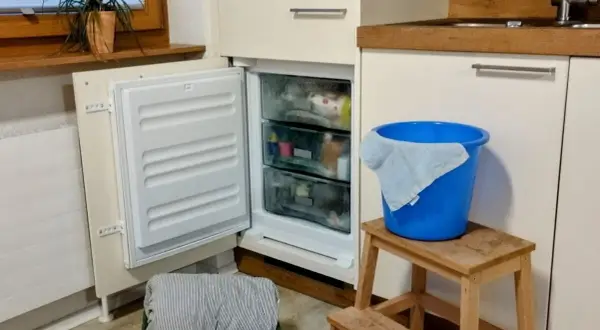 Vriezer niet goed dicht gedaan, met een blauwe emmer en doek klaar voor de ontdooiing.