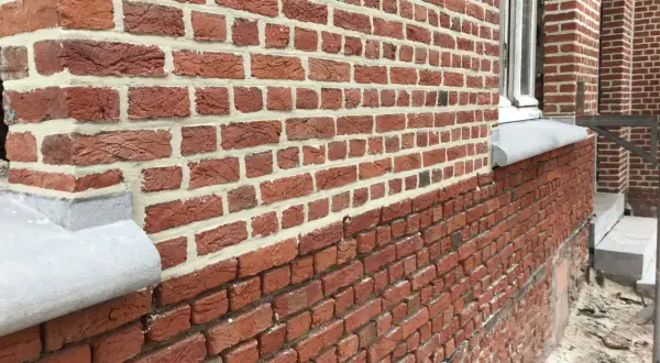 Gedetailleerd zicht op een nieuwe gevel plaatsen met rode bakstenen en wit voegwerk. De textuur van de stenen is duidelijk zichtbaar.