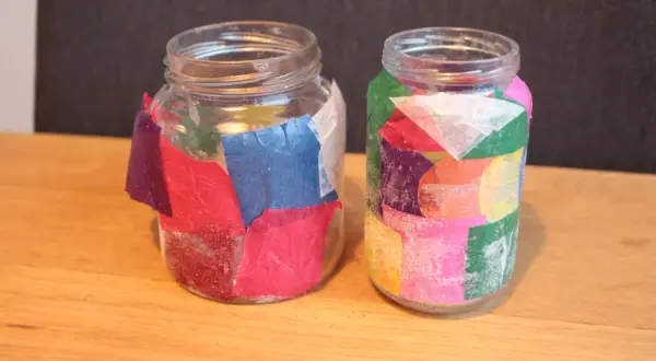 Twee glazen potjes, versierd met gekleurd papier en glitter, klaar voor kerst. Leuk om kerst potjes te maken!