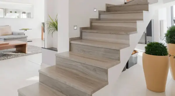 Moderne trap met houten look bekleding, perfect voor trap bekleden ideeen. Sfeervolle verlichting en planten maken het geheel af.