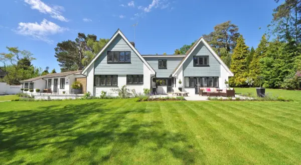Een ruime woning met een aangebouwde garage, omringd door een perfect gemaaid gazon en bomen. Dit is een voorbeeld van wat een kangoeroewoning kan zijn: een woning met een apart woongedeelte.
